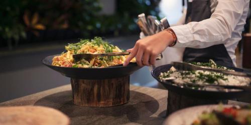 a person reaching into a bowl of food on a table at Fjelsted Skov Hotel & Konference in Ejby