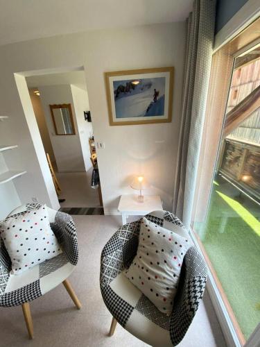 un salon avec deux chaises et une table et une fenêtre dans l'établissement Les Chalets De Superd Fraxinelle - Bel appartement cosy 8 personnes à Superdévoluy MAE-8174, à Saint-Étienne-en-Dévoluy