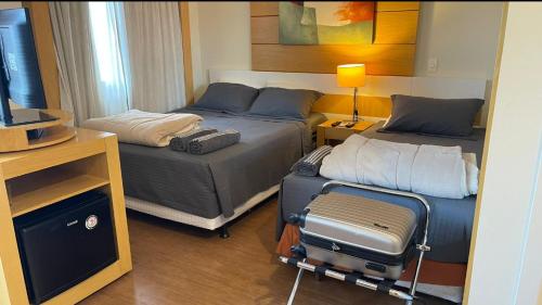 a hotel room with two beds and a suitcase at Flat Aeroporto Congonhas in Sao Paulo