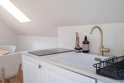 a white kitchen with a sink and a bottle of wine at Lille villa med havudsigt og privat sauna in Espergærde