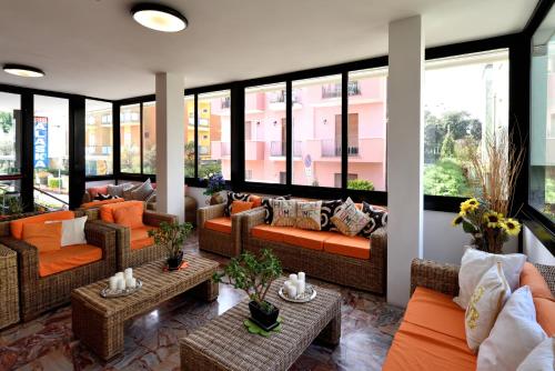 a living room with couches and tables and windows at Hotel Alaska in Rimini