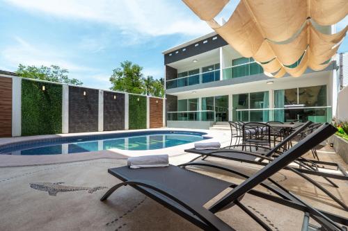 a house with a swimming pool and a bunch of chairs at Villas Acapulco Punta Diamante in Acapulco