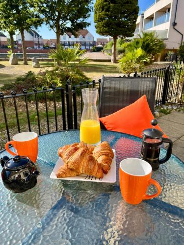 a table with a plate of pastries and a glass of orange juice at Eastbourne Long Beach View, Sovereign Harbour Apartment, Exceptional in Pevensey