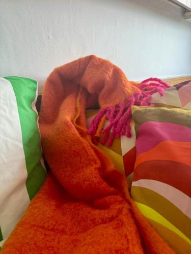 a blanket laying on a bed with colorful pillows at NUMBR25 - self service & low budget Hotel in Graz