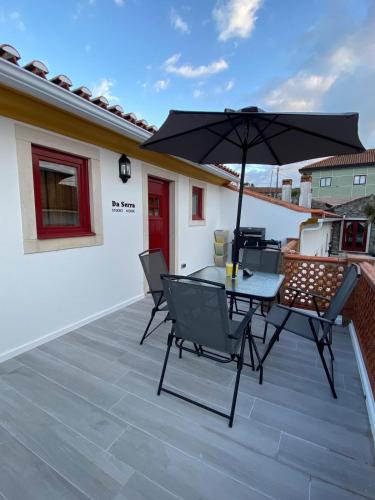 a patio with a table and chairs and an umbrella at Da Serra Studio House in Alqueidão da Serra