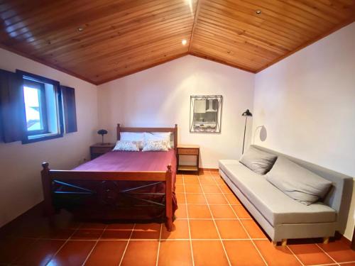 a bedroom with a bed and a couch at Da Serra Studio House in Alqueidão da Serra