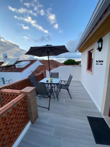 a patio with a table and an umbrella at Da Serra Studio House in Alqueidão da Serra