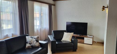 a living room with two chairs and a television at Tgèsa Val in Sedrun