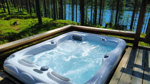 a jacuzzi tub on a deck with a forest at Hossaville Luxe Lake Cabin in Hossa