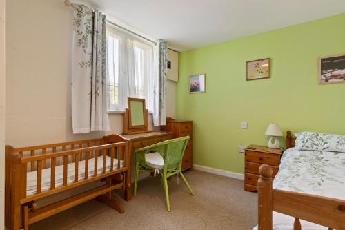 a bedroom with a crib and a bed and a desk at Hedgerow at Gorslwyd - Sound Retreat in Aberporth