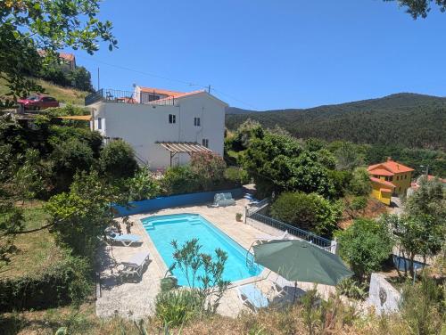a swimming pool with an umbrella and a house at Vila da Fonte - Peaceful 3-bedroom Villa with Private Pool, Central Portugal in Figueiró dos Vinhos