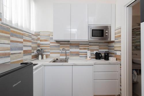 a white kitchen with a sink and a microwave at Università & Strada Nuova - Lovely Suite Scaldasole in Pavia