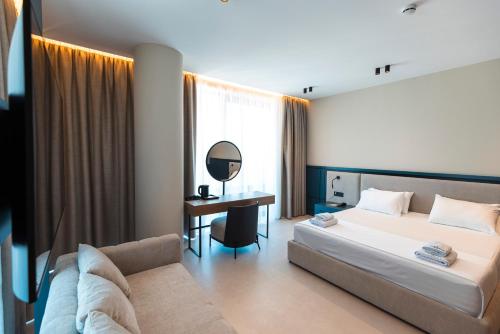 a bedroom with a bed and a desk and a mirror at Green Light Hotel in Ksamil