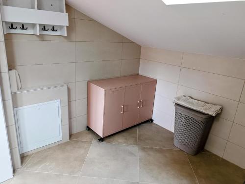 a small bathroom with a pink cabinet and a trash can at Apartma LANA in Koper