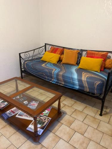 a couch with colorful pillows and a table in a room at La petite maison in Souday