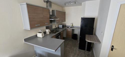 a kitchen with a counter and a black refrigerator at Stylish 1-Bed gated Flat with free Parking and steps from Bournemouth Beach in Bournemouth