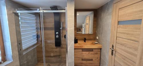 Un baño con ducha con puerta de cristal. en Apartament u Krupy, en Murzasichle