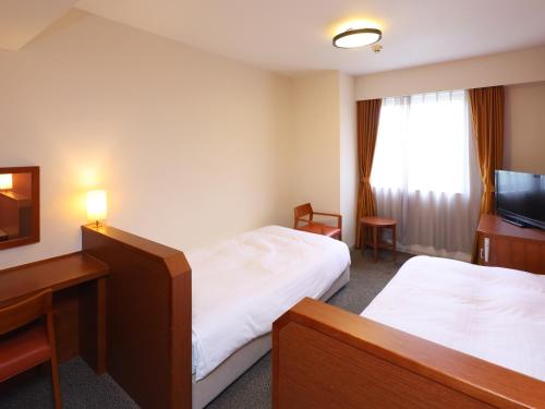 a hotel room with two beds and a television at Dormy Inn Premium Wakayama Natural Hot Spring in Wakayama