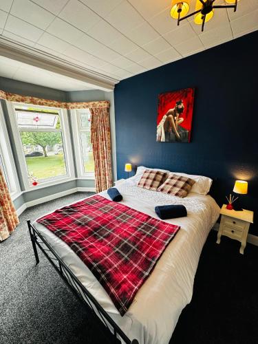 a bedroom with a bed with a plaid blanket on it at Rembrandt Guest House in Great Yarmouth