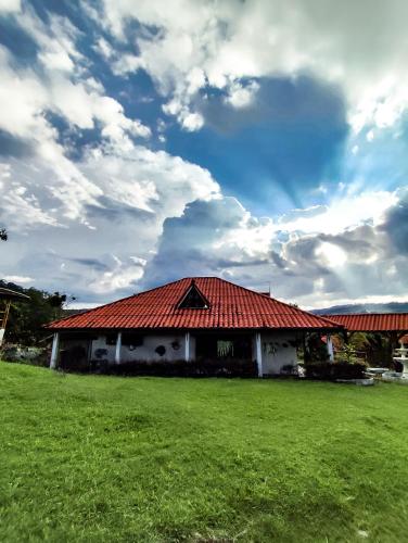 a house with a red roof on a field at Hacienda Ecoturistica la libertad in Moniquirá