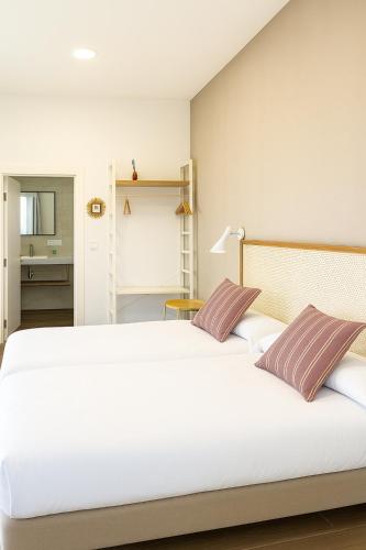 a bedroom with a large white bed with two pillows at Langre Homely Rooms in Galizano