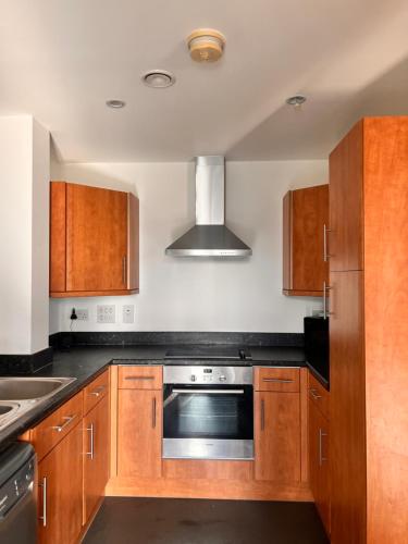 a kitchen with wooden cabinets and a stainless steel oven at Relaxing city base with great access to transport in London