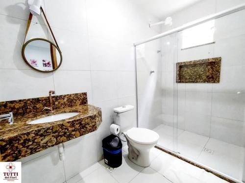 Un baño con inodoro, lavabo y ducha. en Pousada Tutti Del Fiori, en Maracás