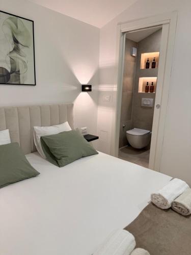 a bedroom with a large white bed and a bathroom at Casa Verde in Donji Zemunik