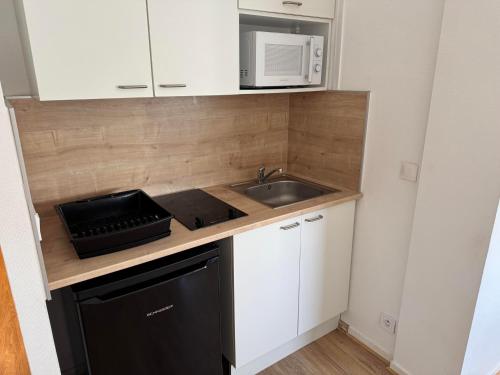 une petite cuisine avec un évier et un micro-ondes dans l'établissement Sea Oceane, à La Rochelle