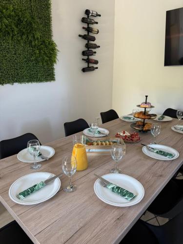 a wooden table with white plates and wine glasses at Casa Verde in Donji Zemunik