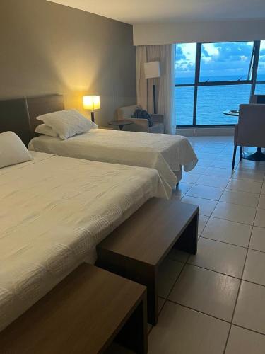 a hotel room with two beds and a view of the ocean at Beira Mar - Flat Beach Class Internacional - Boa Viagem 20º andar in Recife