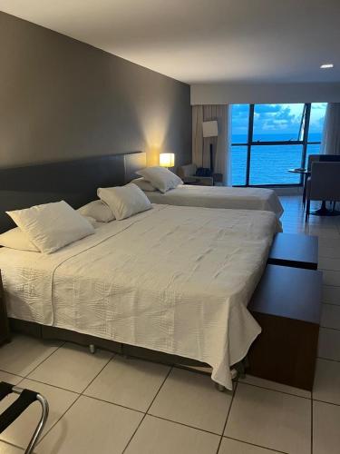 a large bed in a bedroom with a view of the ocean at Beira Mar - Flat Beach Class Internacional - Boa Viagem 20º andar in Recife