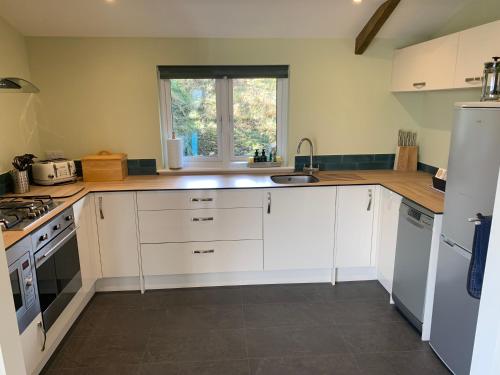 a kitchen with white cabinets and a sink and a window at Field End in Liskeard