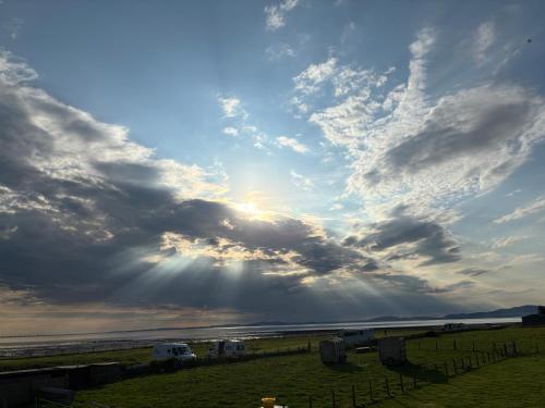 a cloudy sky with the sun in a field at Sea view cottage in Allonby