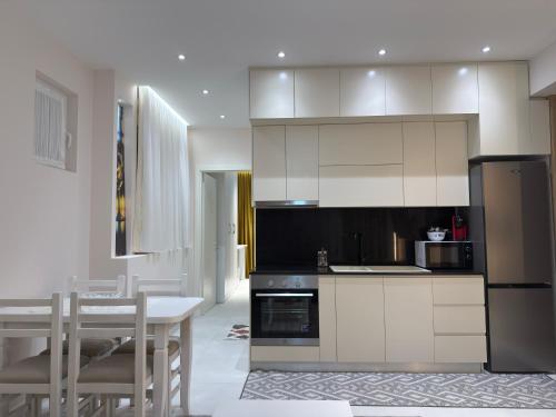 a kitchen with white cabinets and a table and a dining room at City View Apartments in Durrës