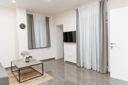 a white living room with a table and a tv at Guesthouse Papac in Stolac