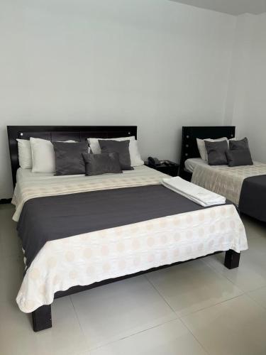 two beds sitting next to each other in a room at Hotel El Potrillo in Puerto López