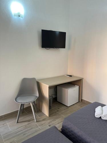 a desk with a chair and a television on a wall at S'Istella Affittacamere in Tinnura