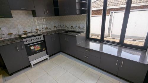 a large kitchen with gray cabinets and a stove at Kigali White home in Kigali