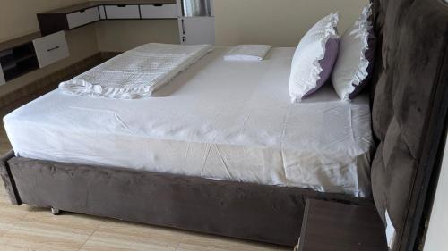 a large bed with white sheets and pillows on it at Kigali White home in Kigali