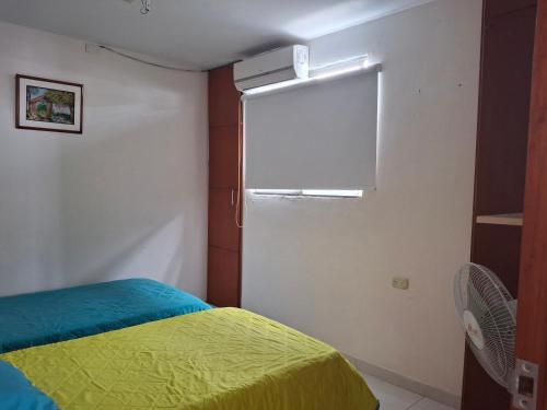 ein Schlafzimmer mit einem Bett mit einer gelben Decke und einem Fenster in der Unterkunft MALALA3 depa amoblado in Sincelejo