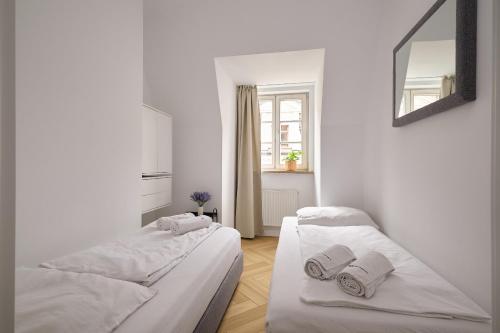 two beds in a white room with a mirror at Solny Square Aparthotel in Wrocław