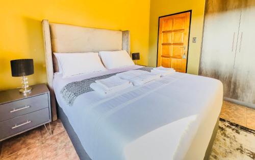 a large white bed in a room with a night stand at Melville Penthouse With Stunning Views in Johannesburg