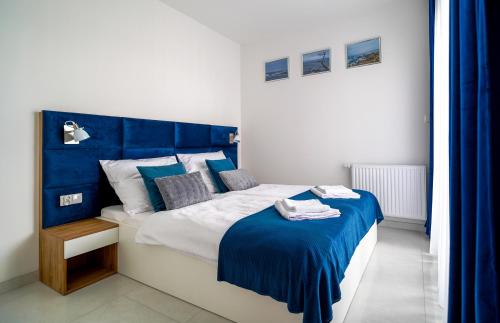 a bedroom with a bed with a blue headboard at Lulu Apartments - DEEP BLUE LAGOON apartament dwupokojowy - parking, Netflix - 350m od plaży! in Grzybowo
