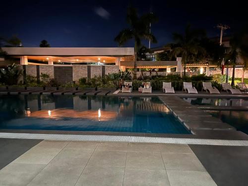 a swimming pool with chairs and a building at night at Hailey's Place in Bacolod