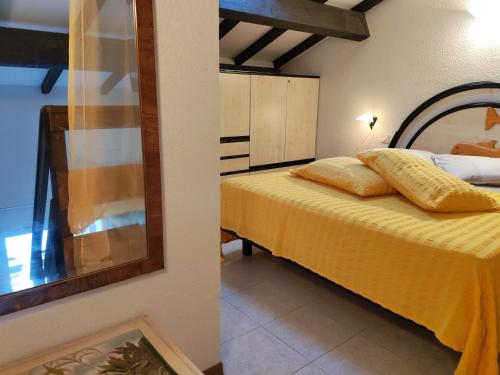 1 dormitorio con 1 cama con sábanas amarillas y espejo en Le Rêve de Mer, en Ghisonaccia