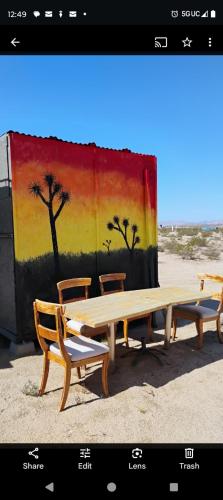 two picnic tables and two chairs in front of a painting at The Yurt at Tribal Camp in Joshua Tree