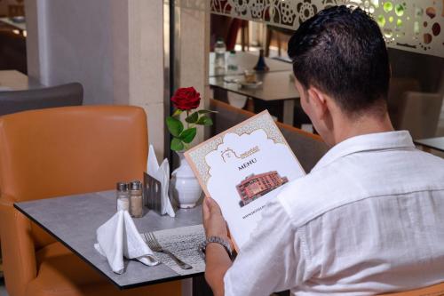 a man sitting at a table reading a book at Hotel Palais Al Bahja in Marrakech