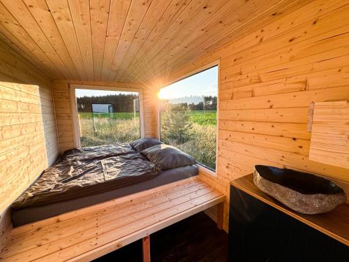 Una cama en una habitación de madera con ventana. en Maringotka uprostřed ničeho, en Třemošná