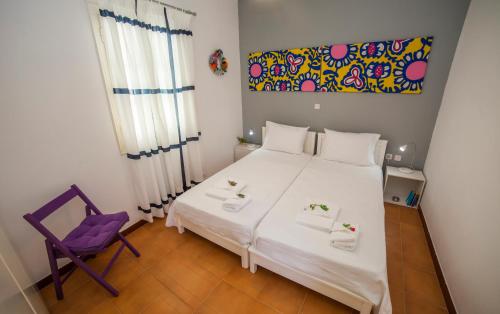 1 dormitorio con cama blanca y silla morada en Family Home PortoKatapola, en Katápola